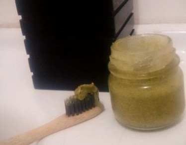 Pequeno vidro contendo pasta dental e escova ao lado