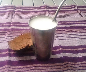 copo de metal sobre pano rosa contento lassi e canudo