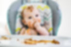 Baby sitting in height chair messily eating food