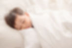 Toddler sleeping under white sheets