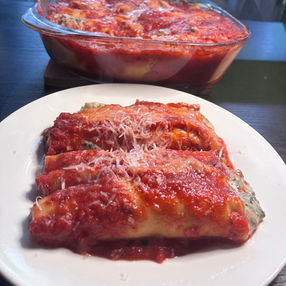 Manicotti with tomato sauce on a white plate.