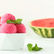 A white bowl with scoops of pink watermelon sorbet with cut watermelon in the background.