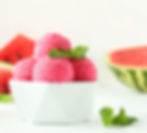 Close-up view of a bowl filled with vibrant melon sorbet topped with fresh mint leaves
