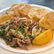 Plate of herb-tossed squid with lemon wedges and crusty bread on a white dish on a table.