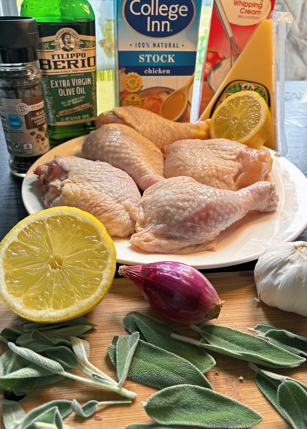 A plate of raw chicken quarters surrounded by other ingredients for this recipe.