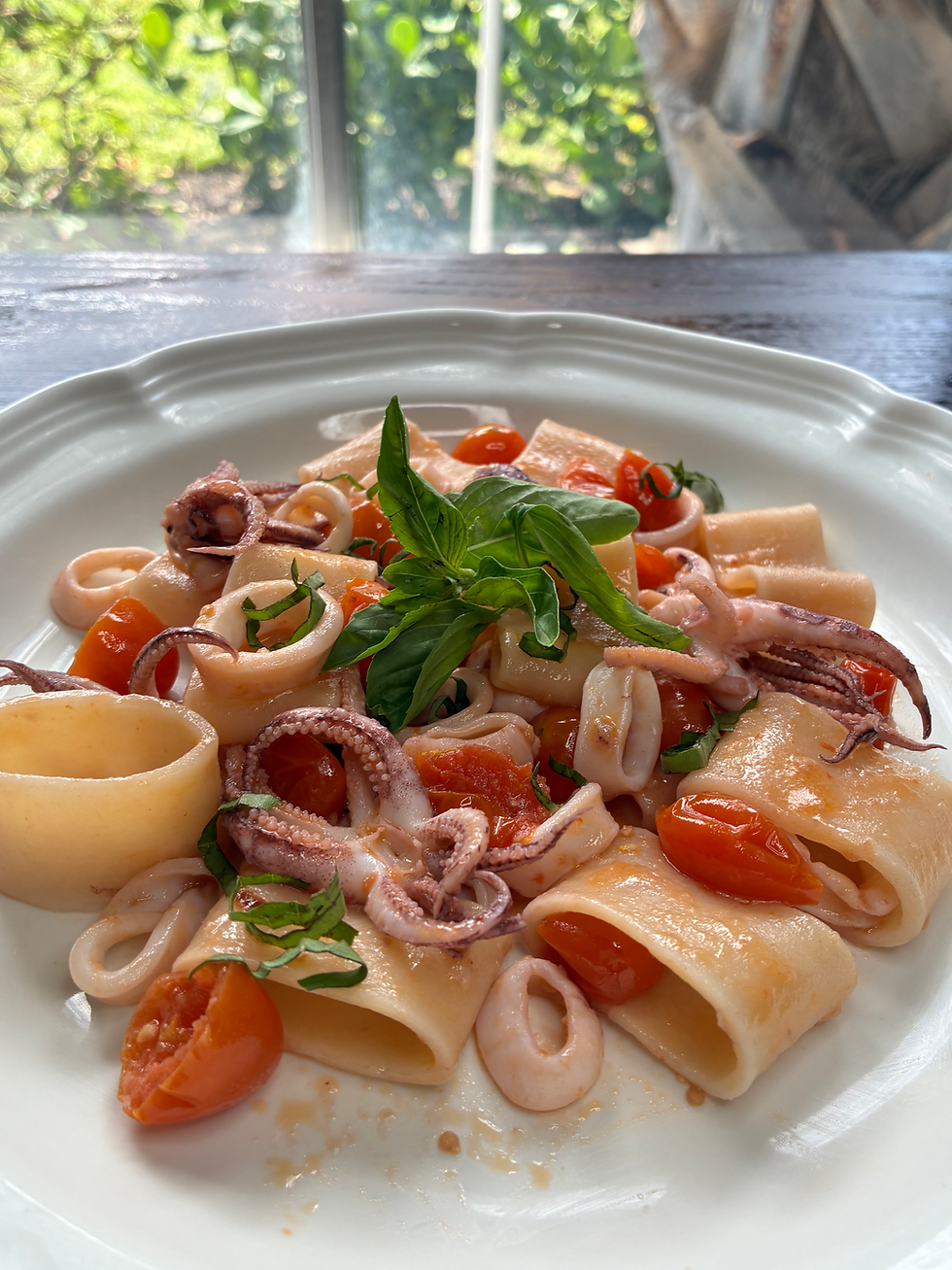 A plate of circular pasta with calamari ring and tentacles.