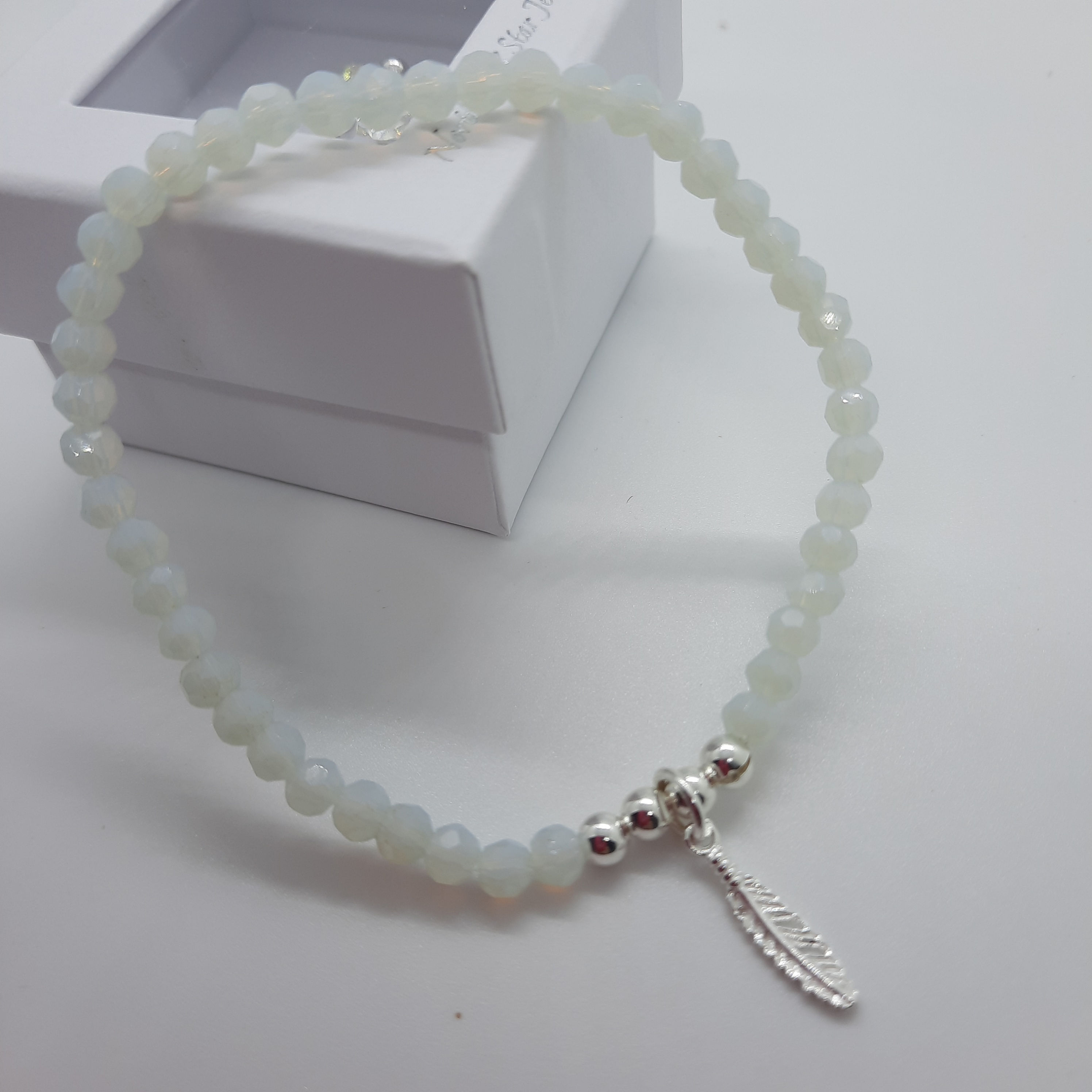 Faceted opalite beaded stretch bracelet with sterling silver feather charm.