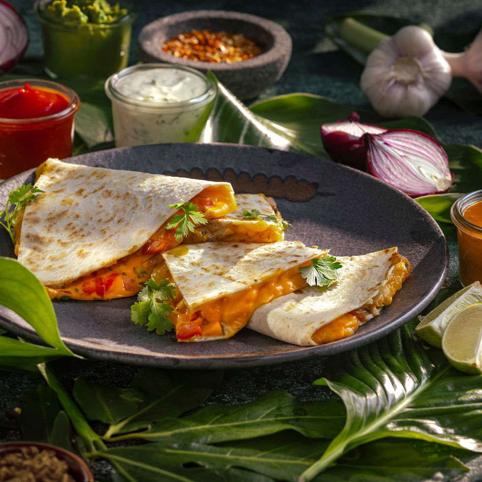 Foodfotograf München – Herzhafte Quesadillas auf dunklem Steinzeug zwischen tropischen Blättern – Kitchenkiss