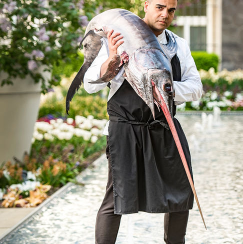 Mitarbeiterfotografie – Einzigartiges Portrait eines Kochs mit frischem Schwertfisch im Außenbereich des Hotels – Kitchenkiss Studio