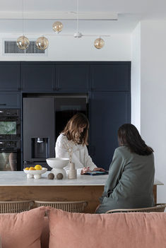 שתי בנות על אי במטבח כחול וספה בגוון אפרסק מציצה