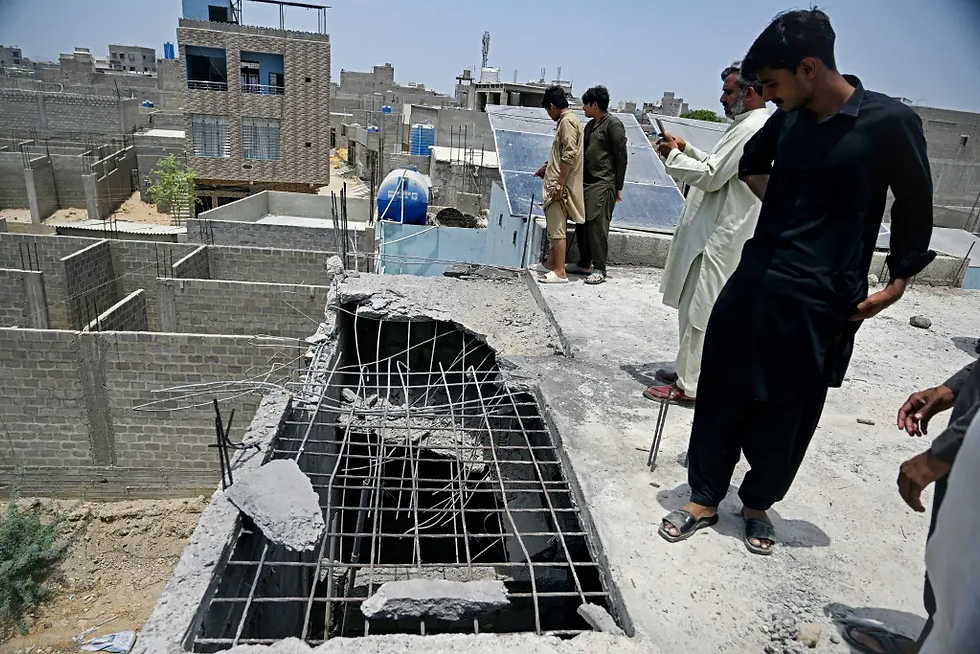 Residents gather on the roof of a damaged house at the site where an alleged drone was shot down in Karachi on May 8, 2025.