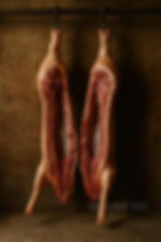 Two sides of pork hanging on the rail