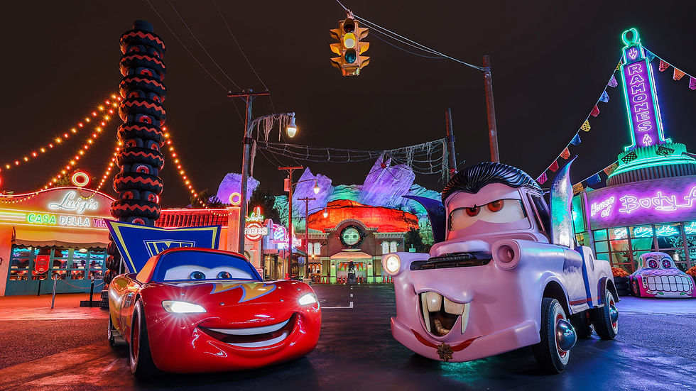 Lightning McQueen and Mater in neon-lit Radiator Springs at night, with colorful Cars-themed shops and glowing signs.