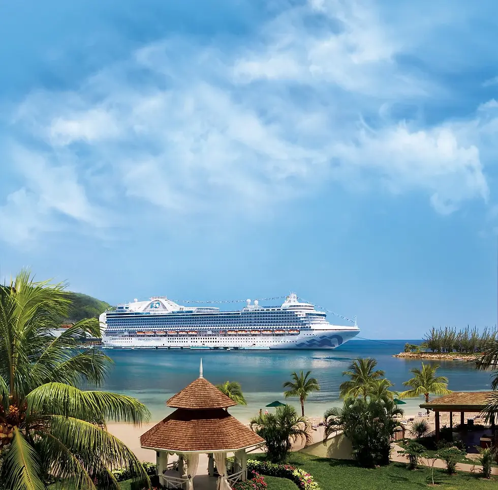 Cruise ship sails near a tropical beach with palm trees, a gazebo, and clear blue skies. Lush green vegetation in the background.