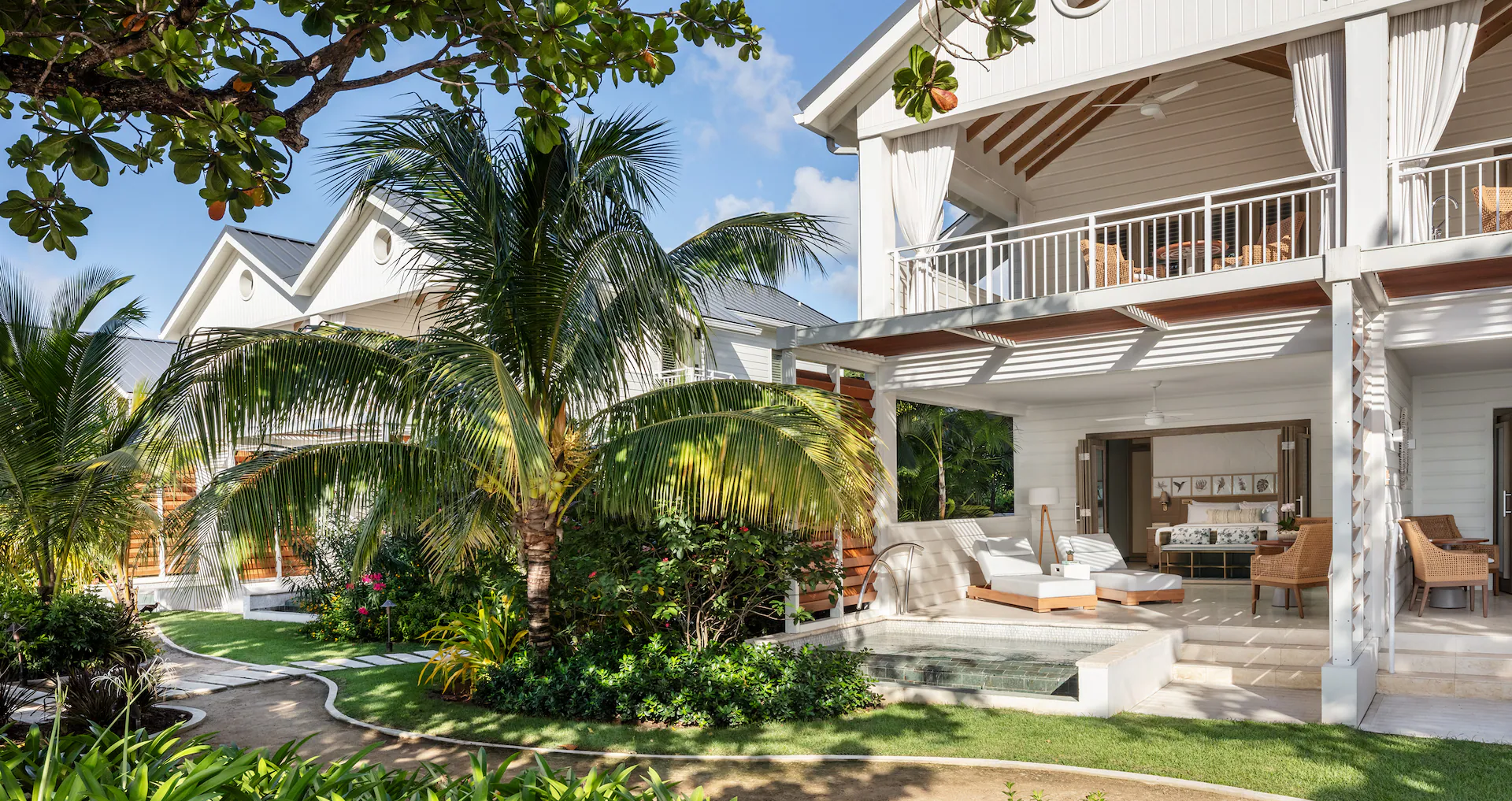 A two story room at a resort with a tropical setting.