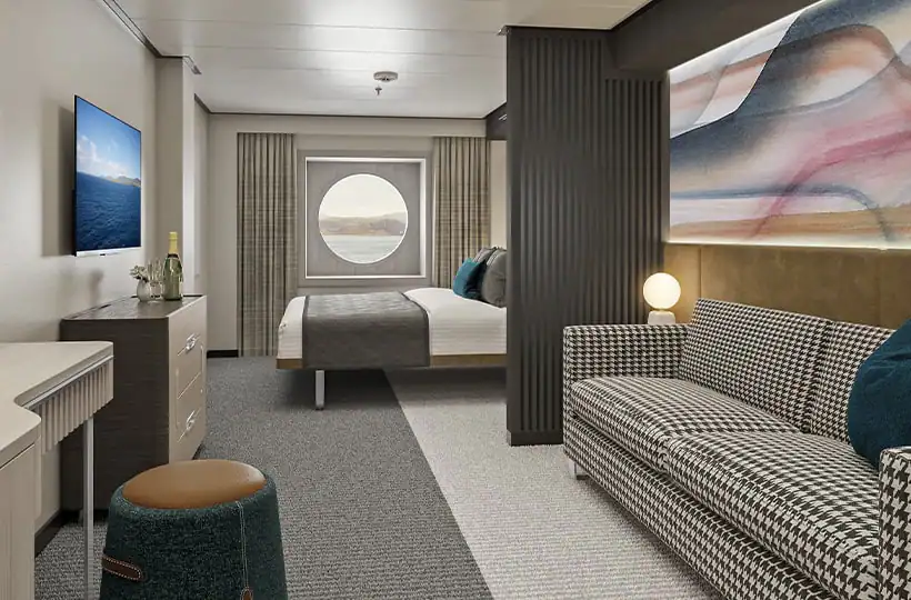 A room with a bed, couch, mirror, and TV. The room is decorated in black, white, and teal. There is a view of the ocean.