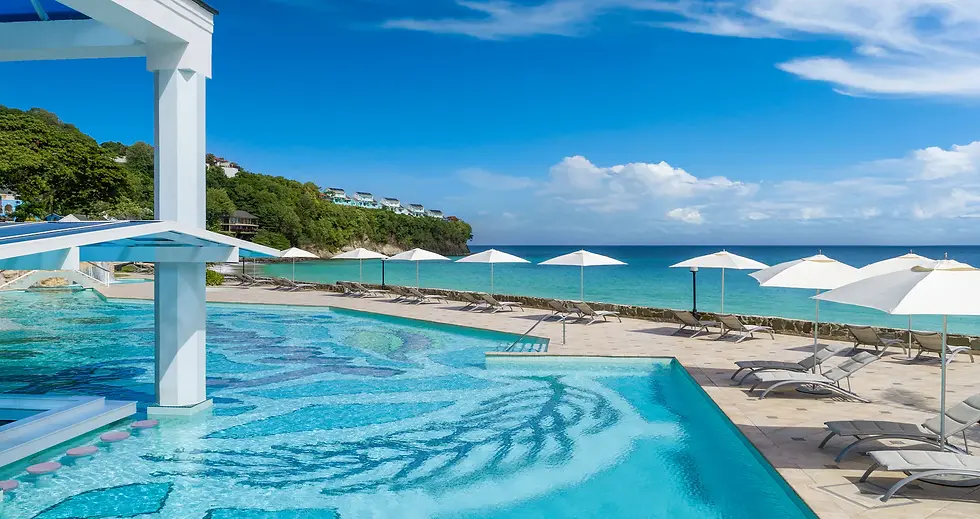 Luxury seaside resort pool with white umbrellas and lounge chairs beside turquoise ocean under a bright blue sky
