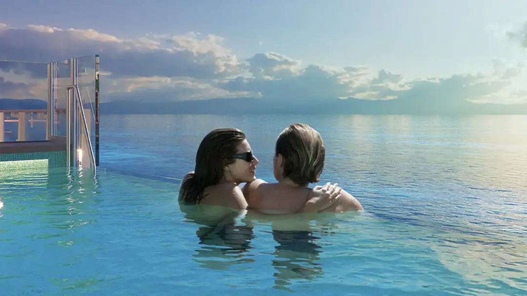 A couple enjoying a hot tub looking at the ocean at sunset.