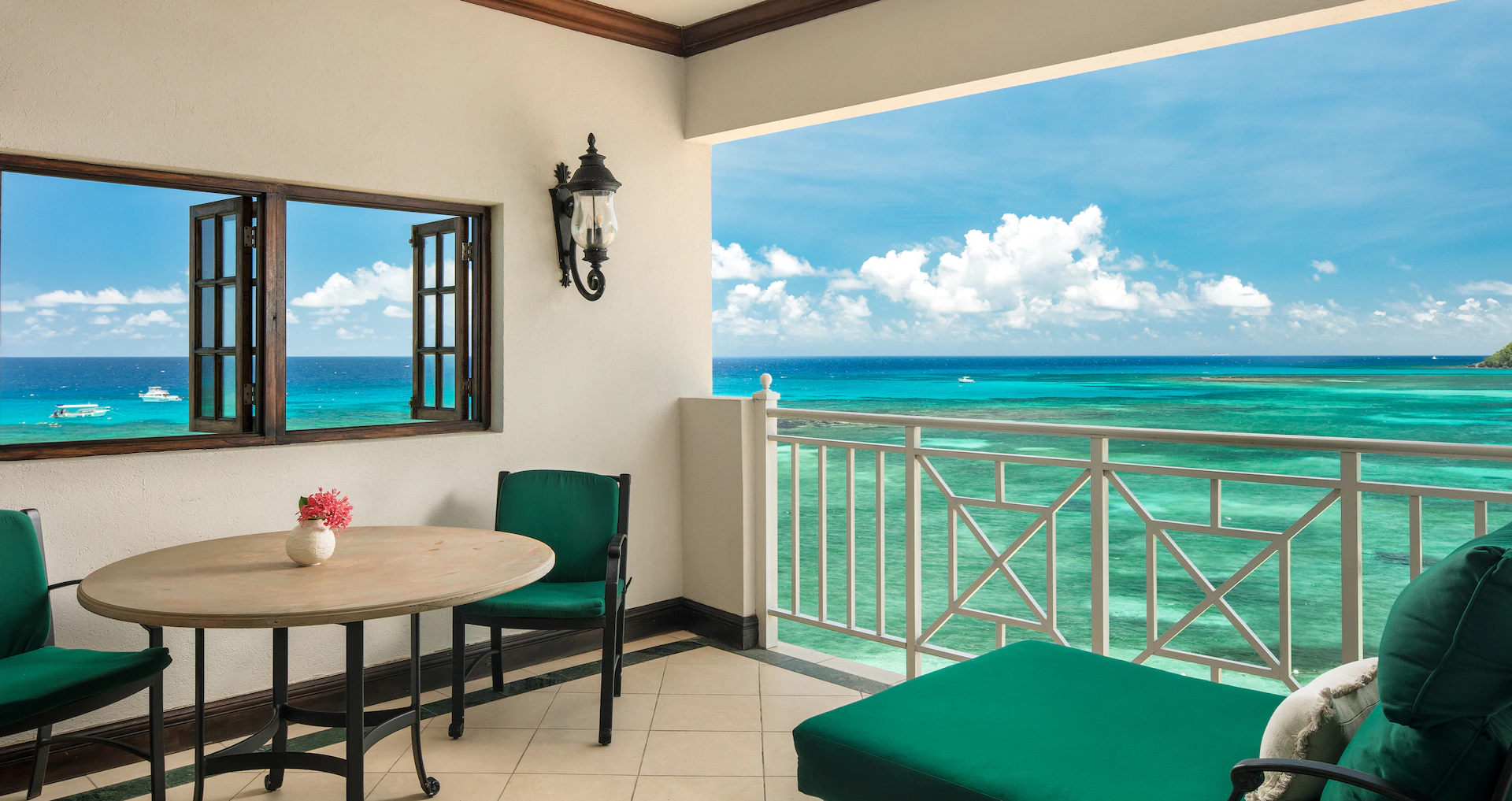A balcony with teal and neutral overlooking teal waters.