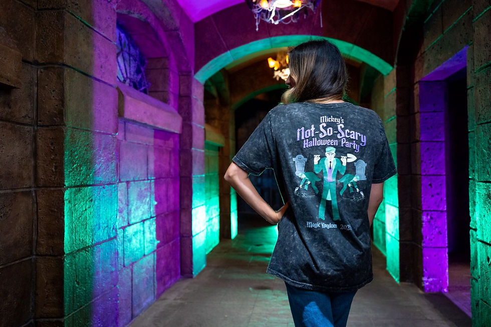 Person wearing "Mickey's Not-So-Scary Halloween Party" shirt in colorful, illuminated stone corridor. Mood is festive with purple and green lights.