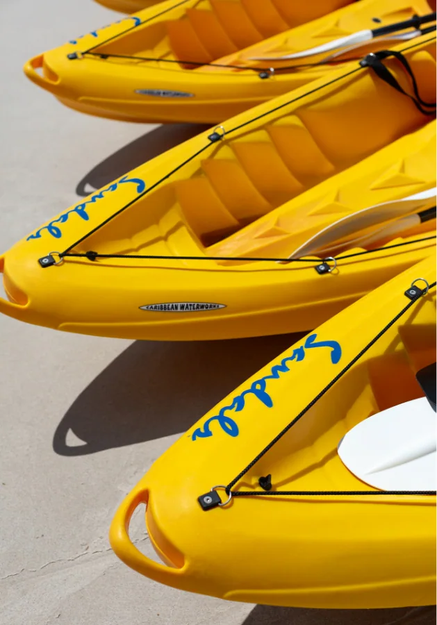 The front of three yellow kayaks with the Sandals logo on them.