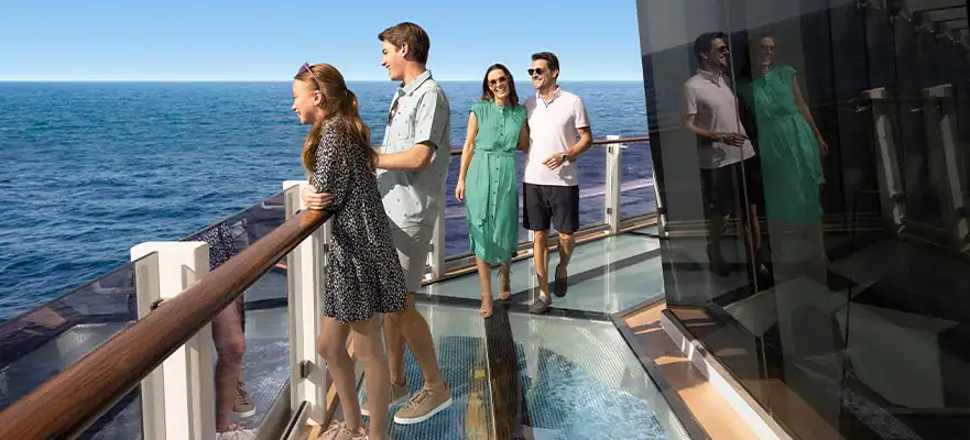 A family standing on a seethrough deck of a cruise ship. The ocean is in view.
