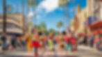 Characters in colorful costumes parade on a sunny street with palm trees. Festive atmosphere, building signs include "Disney Theater."