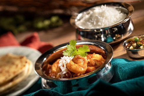 Cape Malay Shrimp Curry – Garam masala, turmeric, cumin-coconut curry sauce, aromatic basmati rice, cucumber sambal, and butter roti in a silver dish.