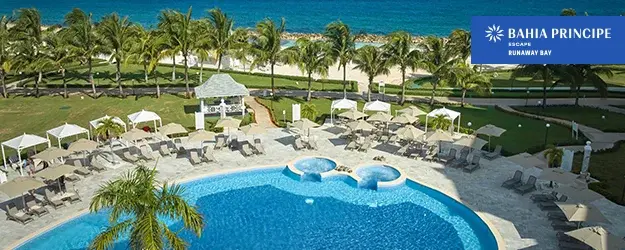 Resort pool with loungers, palm trees, and ocean view at Bahia Principe Escapes Runaway Bay.