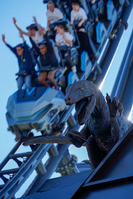 VelociCoaster on its track behind raptor statue.