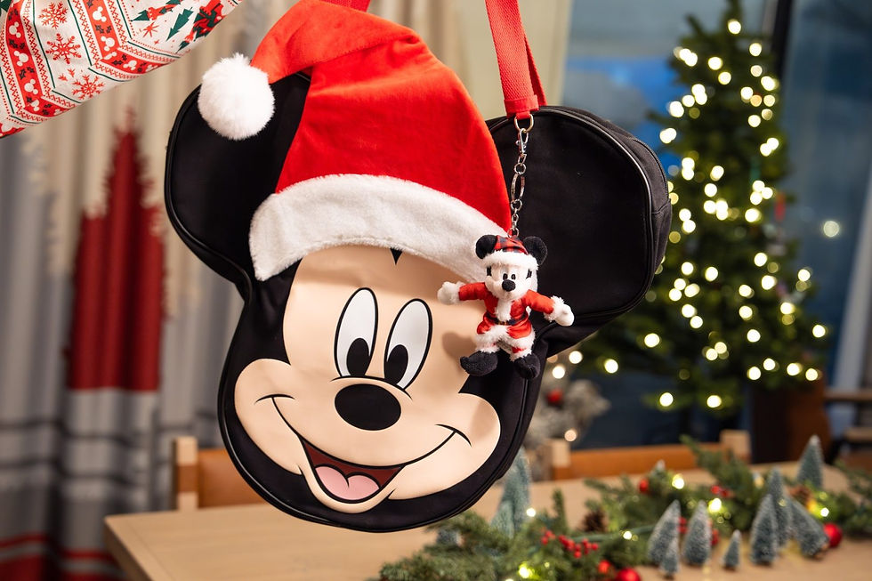 Mickey-shaped bag with Santa hat and keychain, festive table setting, Christmas tree in background, cozy holiday ambiance.