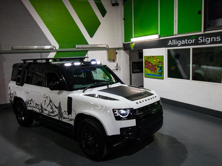 A white defender vehicle with graphics of a mountain range.