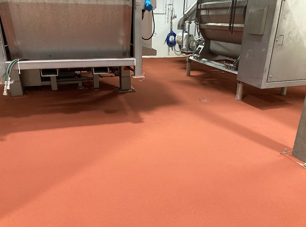 Red FDA approved indu-crete flooring in manufacturing plant alongside large steel machinery