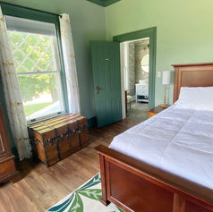 A photo of the Betty Jean room decorated with green walls and beautiful wood king size bed.