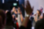 Musicians and singers lead a vibrant worship service as the congregation raises their hands in praise.
