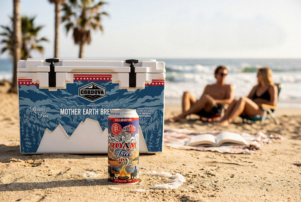 Beachside cooler and Roam Free IPA can in front of a blurred couple relaxing on the sand by the ocean and palm trees