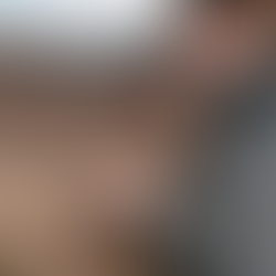 Person in a dark jacket holds a thermometer against a brown horse's side, checking temperature. Clear sky and grassy background.