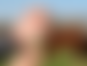 Close-up of hands holding a syringe and vial, preparing an injection. Two brown horses graze in a sunny, fenced field background.