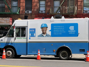 Blue and white Con Edison truck with "Biodiesel Power" parked on a city street. Construction workers nearby. Santa Cruz Records in background.
