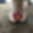 A close-up of an injured horse hoof with red and yellowish sore, on a concrete floor. The setting is a stable with blurred blue door.