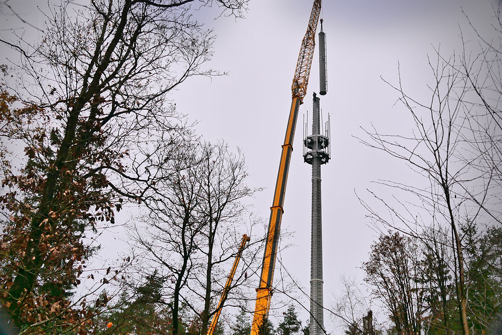 Mobilkran setzt Funktechnik-Segment auf Betonschaft im Wald Unterlüß.