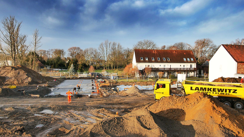 Baugeschehen am „Eulenhof“; LKW liefert Material, Arbeiter gießen erste Bodenplatte.
