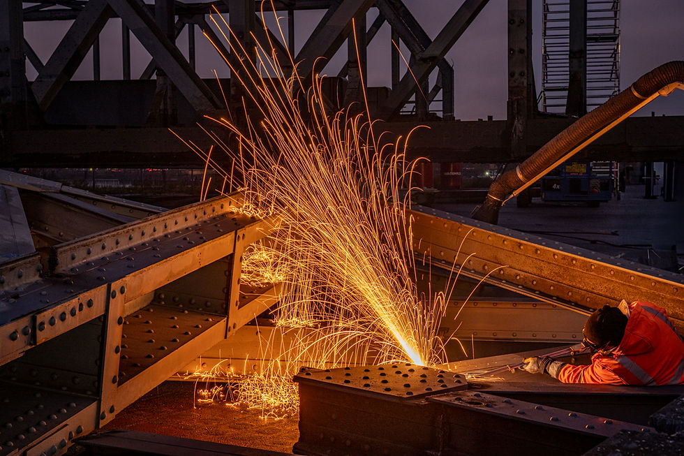 Metallarbeiter bei Brückendemontage mit Funkenflug auf dunkler Baustelle.