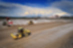 Walze und Planierraupen bei Bodenstabilisierung auf Schulbau-Baustelle.