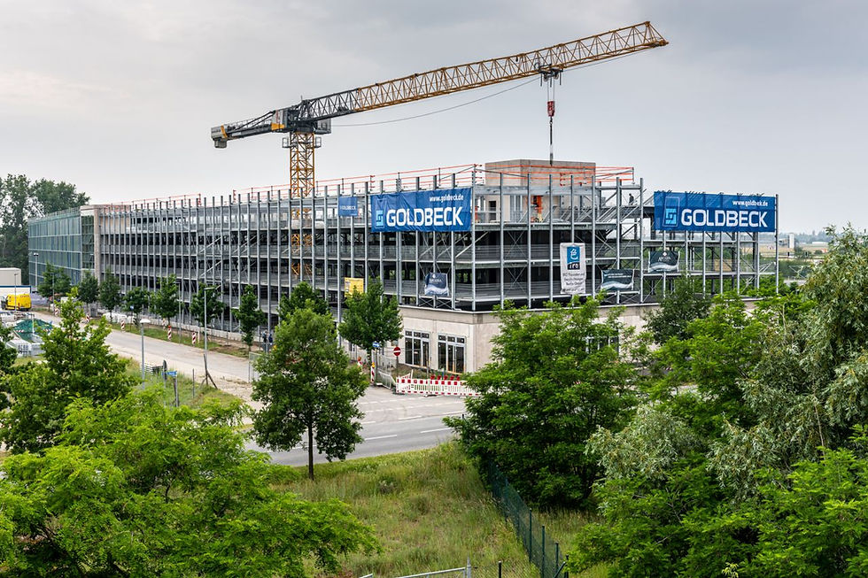 Eingerüstetes Parkhaus-Skelett mit Bannern und Kränen bei Montage der Fertigteile.