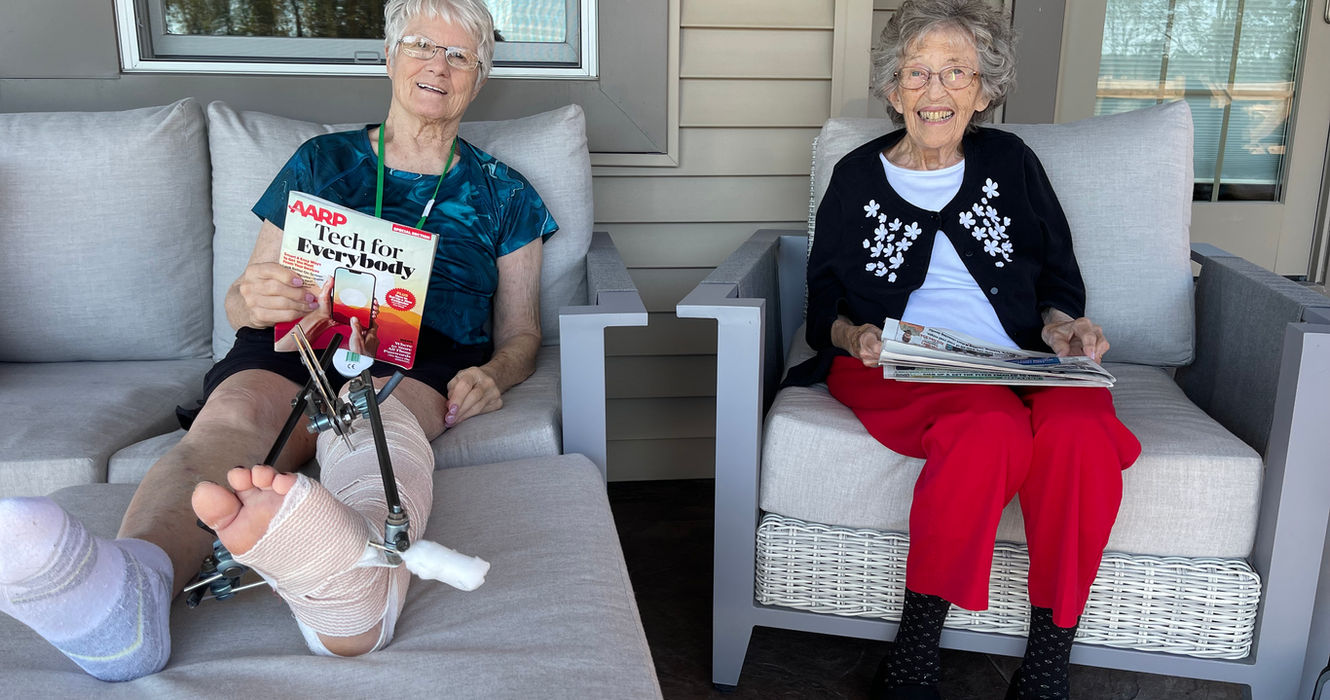 Residents enjoying a quiet afternoon reading together on the covered patio.