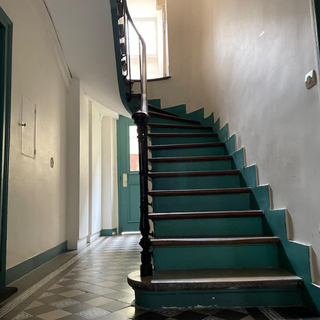 Escalier en colimaçon bleu et bois dans un hall d'entrée.