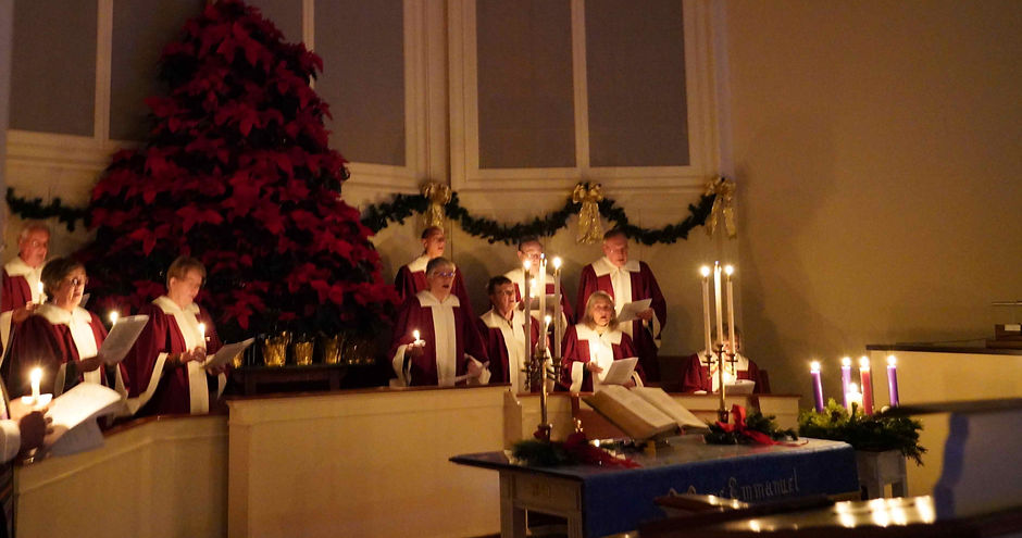 church choir singing on christmas eve holding candles in a darkened sanctuary