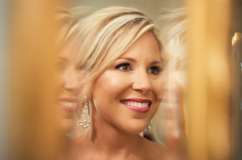 closeup reflection of a bride in a beveled mirror as she smiles - Julia Bailey