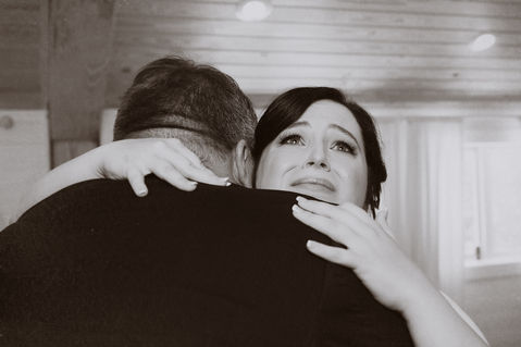 A woman fights back tears while she hugs her Father - Julia Bailey